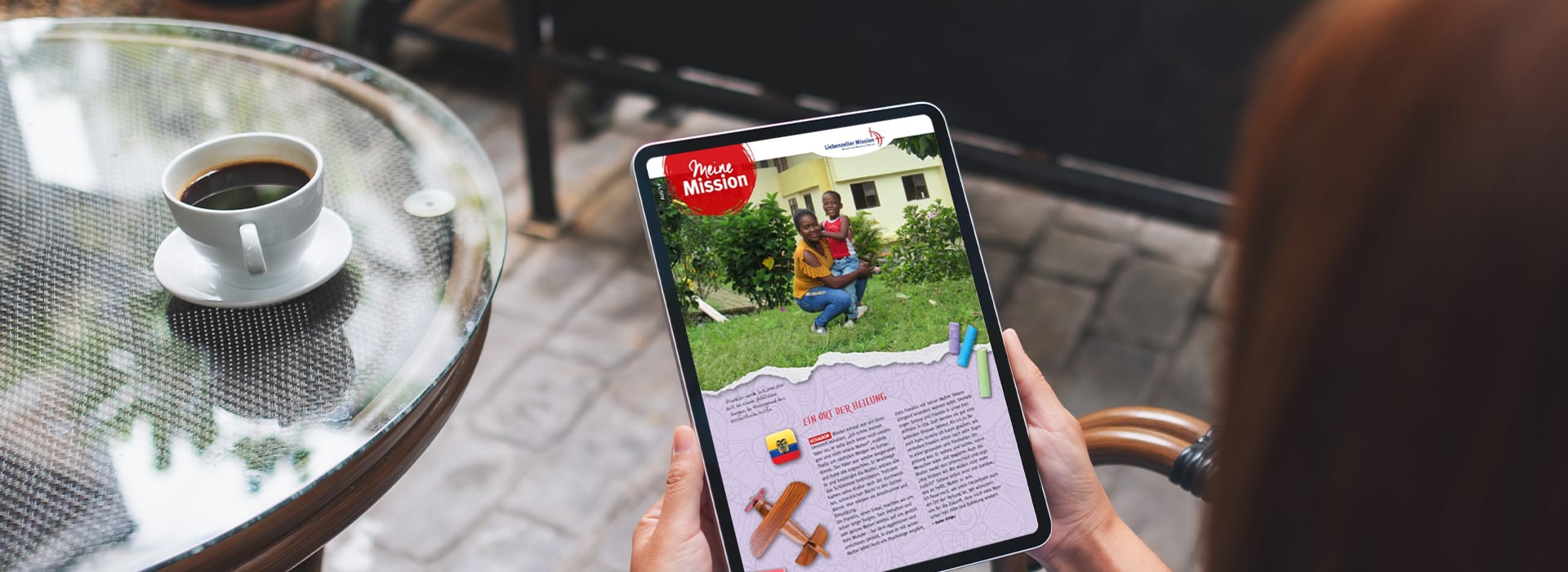 Eine Person, die ein Tablet in der Hand hält und draußen neben einem Glastisch mit einer Tasse Kaffee einen Artikel mit Bildern liest.