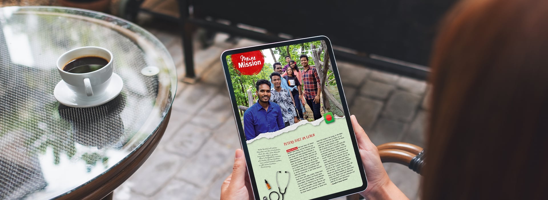 Eine Person liest auf einem Tablet bei einer Tasse Kaffee in einem Straßencafé einen Artikel über eine Gruppe lächelnder Menschen.