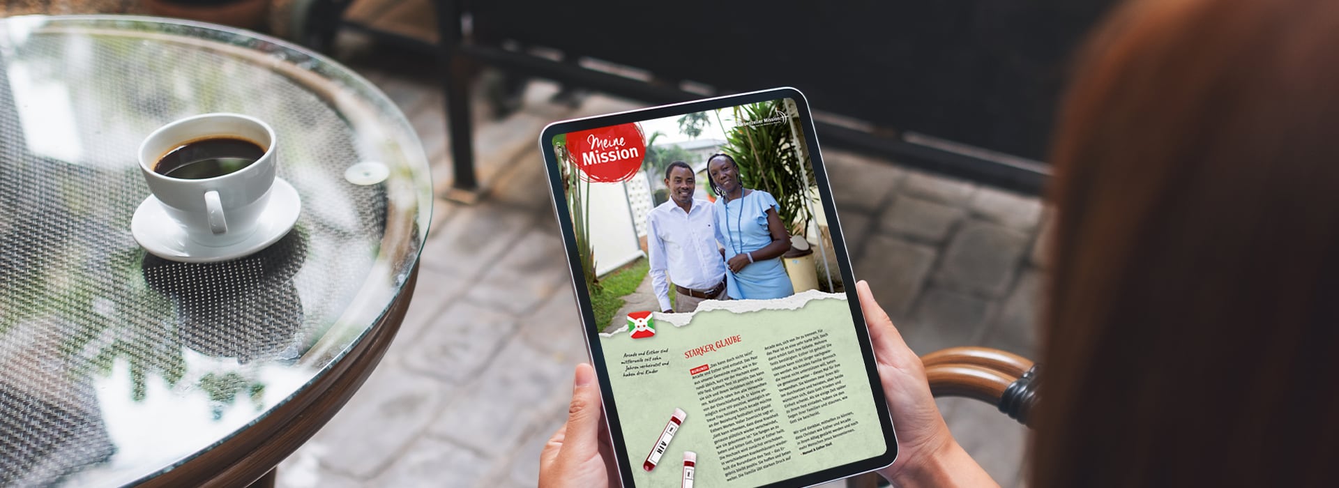 Eine Person liest an einem Café-Tisch bei einer Tasse Kaffee ein digitales Magazin auf einem Tablet.
