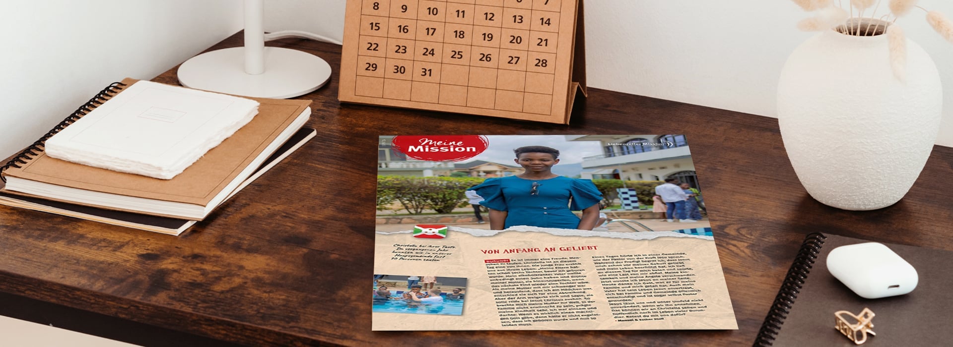 Auf einem Schreibtisch liegt neben Notizbüchern, einem Kalender und einer weißen Vase eine Zeitschrift mit einer Frau auf dem Titelblatt.