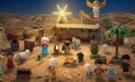 LEGO-Krippe bei Nacht mit Figuren, Tieren, einem Engel und einem Stern über einem Stall in einer Wüstenlandschaft.