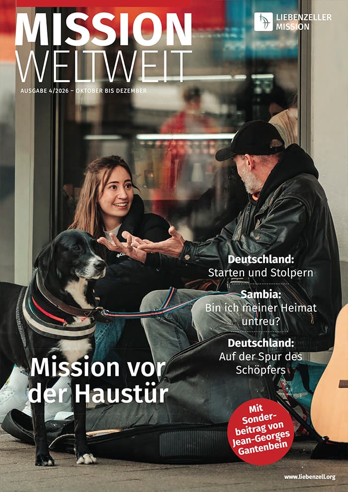 Eine Frau sitzt lächelnd auf dem Boden und unterhält sich mit einem Mann, der auf einer Bank sitzt; neben ihr steht ein Gitarrenkoffer.