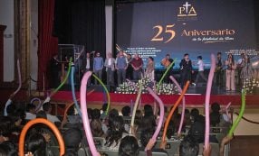 Menschen auf der Bühne bei einer Veranstaltung zum 25-jährigen Jubiläum; das Publikum winkt zur Feier des Tages mit bunten Luftballons.