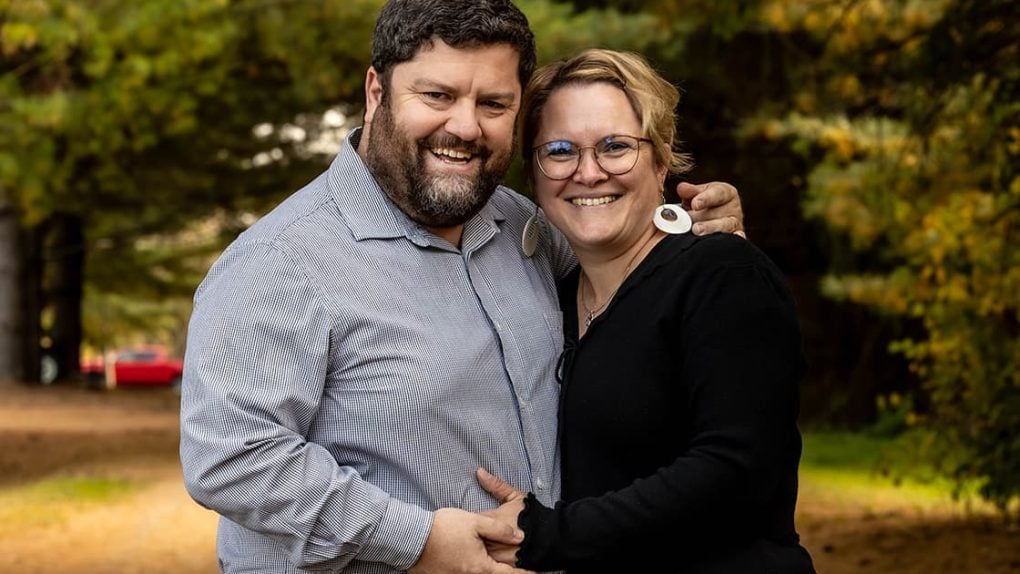 Ein Mann und eine Frau, die im Freien lächeln und Händchen halten.